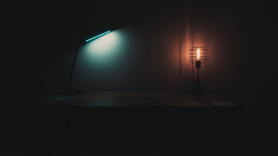 Different lamps with cold and warm lights placed on table in dark room